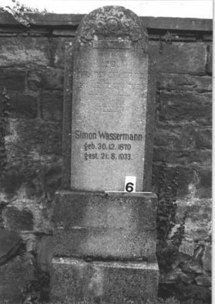 Grabstein 6 (Index: 100114404) Material: Kalkstein Zustand: verwittert Maße HxBxT: 158x54x27 cm Beschreibung: Stele, getreppter Sockel, eingezogener Rundbogenabschluß Symbolik: Blumenschale: Grabstein 6