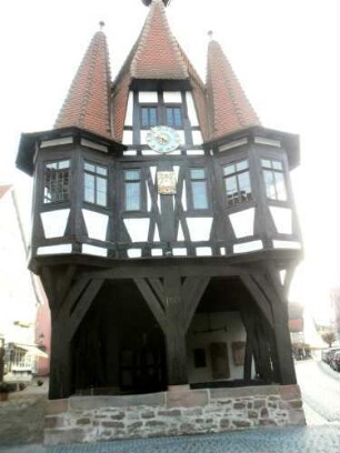 Stadtbild-Rathaus-Ansicht von Westen-mit offener Erdgeschoßhalle sowie Obergeschoß mit Fachwerkstruktur (verzapft) und Eckerkern in Übersicht