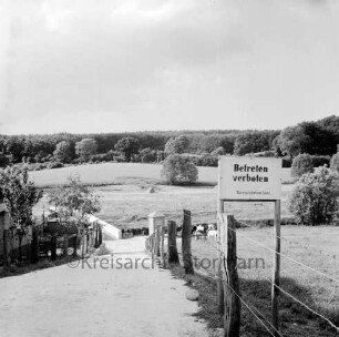 Travetal: Straße zur Fußgänger- und Viehtriebbrücke: rechts Zaun mit Verbotsschild: im Hintergrund Kneeden