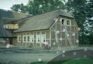 Papierholz 1: Gaststätte Zur Hahnheide: giebelständiges Bauernhaus mit Reetdach: Teilansicht: links Traufseite Altbau mit Tür: Bildmitte neuer Querbau bei Fertigstellung, rückwärtige Traufseite, Giebelseite, Leitern