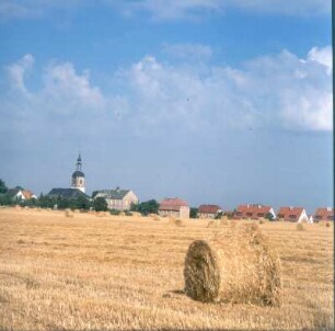 Burkhardswalde. Ansicht mit Dorfkirche von Nordost. Im Vordergrund abgeerntetes Feld mit Strohballen