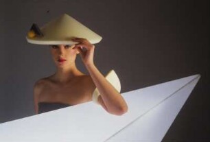 Model in Schaumstoffmode : Model mit gelbem Schaumstoffhut hinter einem Neonleuchtkörper