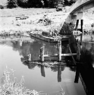 Klein Barnitz: Trave: Brückenbau: Reste der alten Holzbrücke: dahinter Boot mit Arbeitern: an Uferböschung Holzbalken: rechts oben neue Fußgängerbrücke