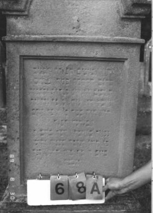 Grabstein 68 (Index: 99609704) Material: Sandstein Zustand: stark verwittert, weitgehender Textverlust Maße HxBxT: 182x64x28 cm Beschreibung: Stele, eingezogener Rundbogenabschluß mit Verdachung, Mittelpalmette, rechteckiges Schriftfeld eingetieft, getreppter Sockel, unten rusticaartig: Grabstein 68A