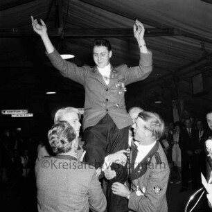 Schützenfest: Veranstalter Schützenverein Reinfeld und Umgebung von 1954 e.V.: Festplatz in der Ahrensböker Straße: im Festzelt: Königsproklamation: Jungschützenkönig Peter Claußen auf den Schultern seiner Schützenbrüder, grüßt mit erhobenen Armen: im Hintergrund Gäste, 2. September 1961