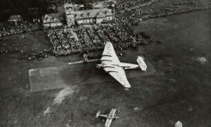 Flugplatz Dresden-Heller, Verkehrsflugzeug Junkers G 38 am Flugtag auf dem Rollfeld mit Zuschauern vor dem Abfertigungsgebäude mit Kontrollturm, Luftbild-Schrägaufnahme