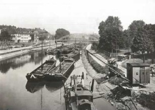 Saarbrücken, Saar : Saarbrücken. Teil der Stadt an der Saar mit Frachtkähnen, Dampfkran und Bagger