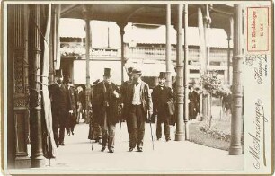 Fünf Personen, Ankunft Kaiser Wilhelm I., König von Preußen in Bad Ems in Zivilkleidung mit Stock in überdachter Passage