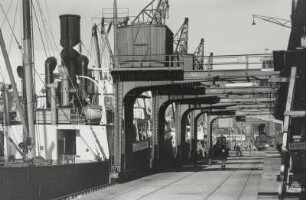Königsberg, Hafen : Königsberg (Kaliningrad/Russland). Hafen. Kaianlage mit zwei Hafenbahngleisen und fünf Halbportalkränen. Blick von Land gegen einen Frachtdampfer