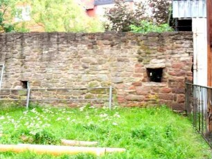 Kirchhofmauer im Südwesten von West (Feldseite) mit Schießscharte in Brusthöhe (runde Kreis- oder Büchsenscharte mit Öffnungwinkel nach außen)-Wehrgang abgetragen