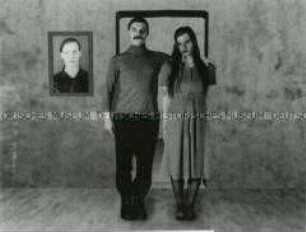 Theaterszene: Mann umarmt eine Frau, im Hintergrund Bild an der Wand (Prämiertes Foto Sonderthema: Familienbilder)