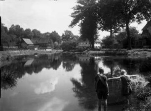 Westlausitz. Blick über einen Teich gegen Wohnhäuser