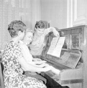 Oberschwester Ruth Neumann aus der Charité in Berlin (Ost) musiziert mit ihren Töchtern am Klavier