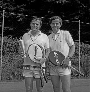 Tennis: Kreisturnier: Tennisplatz des Tennis- und Hockey-Clubs "Blau-Weiß" e.V.: Spieler mit Pokal und weiterer Spieler: hinten Zaun, Hecke, Bäume