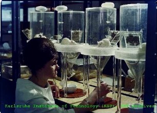 Unbekannte Mitarbeiterin vor den Stoffwechselkäfigen mit Versuchsratten am Institut für Strahlenbiologie (IStB)