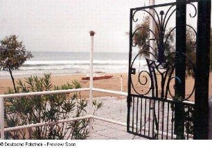 Blick über eine Terrasse auf Strand und Meer