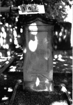 Grabstein 147 (Index: 100105287) Material: Sandstein Zustand: verwittert, unten abgeblättert Maße HxBxT: 114x51x20 cm Beschreibung: Stele, Sockel, rund geschwungener giebelartiger Abschluß mit Verdachung, rechteckiges Schriftfeld eingetieft: Grabstein 147