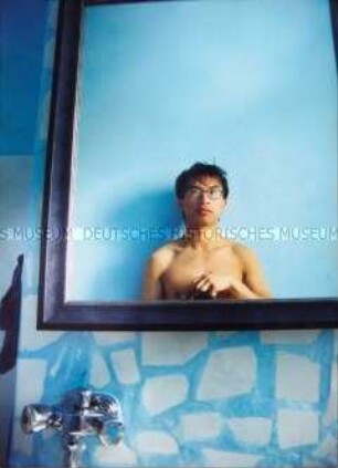 Junger Mann fotografiert sich mit nacktem Oberkörper vor dem Spiegel im Badezimmer (Sonderthema: Ein Bild von mir - Selbstporträts und Selbstdarstellungen)