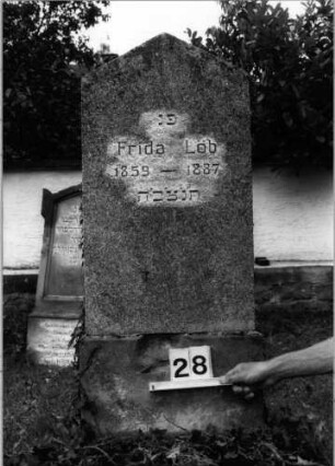 Grabstein 28 (Index: 99804573) Material: Stele Kalkstein, Sockel Sandstein ? Zustand: leicht verwittert Maße HxBxT: 136x50x18 cm Beschreibung: Stele, Sockel, giebelartiger Abschluß: Grabstein 28