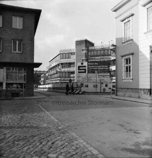 Kreissparkasse Stormarn: Hagenstraße: Zentrale: in Bau: mit Gerüst, Bauschild, Sparkassenemblem, Bauzaun: Fußgänger: rechts Einmündung Weg zum Bürgerpark, Historisches Rathaus: links Einmündung Markt, Eckhaus Altbau Kreissparkasse: Straßenschilder, Verkehrsschilder