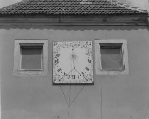 Dresden-Gompitz-Pennrich, Altnossener Straße 44. Ehemaliger Dreiseithof (Steins Hof). Wohnstallhaus (bezeichnet 1776). Detail: Sonnenuhr (1864) zwischen zwei Fenstern an der Giebelseite (Obergeschoss)