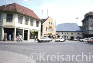 Hude 7, 6, 5: Häuser von links nach rechts: Basar Egler, Schuhmarkt, Drogerie: hinten Blaues Haus, rechts Kaufhaus Haerder: links Einmündung von Mühlenstraße, im Vordergrund rechts Einmündung von Straße Kirchberg