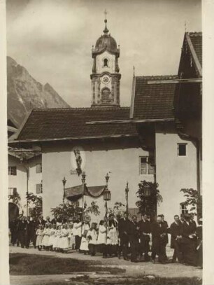 Mittenwald (Oberbayern) Fronleichnamsprozession. Hintergrund: Kirchturm der, von 1738-1740 im barocken Baustil errichteten, katholischen Pfarrkirche St. Peter und Paul