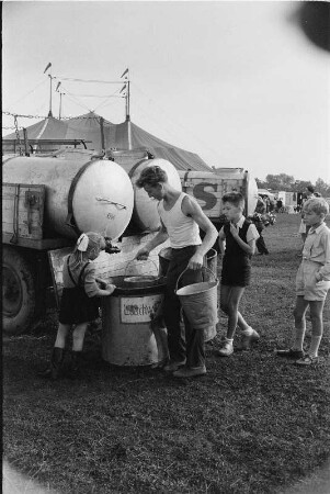 Schausteller mit Kindern an einem Wassertank