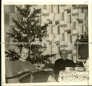 Älteres Paar am Kaffeetisch vor dem Weihnachtsbaum