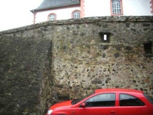Ansicht von Norden-Kirchhofmauer über Ortsseite mit erhaltener Schießscharte (in Brusthöhe aus dem höher gelegenen Kirchhof)-Wehrgang der Kirchhofmauer im frühen 18 Jh abgetragen