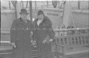 Passagiere (Ehepaar) an Deck des Hochseepassagierdampfers "Bremen", vor zwei Rettungsbooten an der Reling lehnend