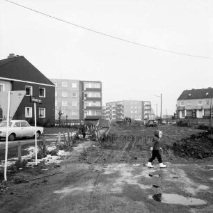 Greifswalder Kehre: Kind vor einer Baustelle von Straßenbauarbeiten im Winter, an den Seiten Wohngebäude: Blick nach Westen