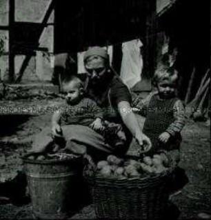 Arbeitsmaid des Reichsarbeitsdienstes mit Kindern beim Verlesen von Kartoffeln
