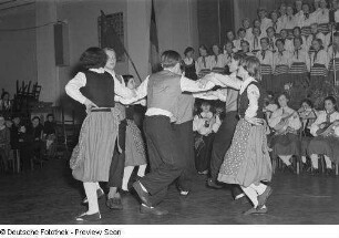 Tanzende Paare in Tracht, Chor und Orchester des Pionierensembles "Julian Marchlewski" der Humboldtschule bei einer Kulturveranstaltung, im Hintergrund Zuschauer