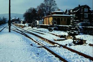 Bahnhof: verschneite Gleisanlagen, im Hintergrund Toilettenhäuschen