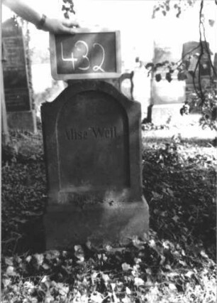 Grabstein 432 (Index: 100111750) Material: Sandstein Zustand: gut Maße HxBxT: 72x36x18 cm Beschreibung: Stele, Sockel, eingezogener Segmentbogenabschluß, Schriftfeld eingetieft mti Rundbogenabschluß Besonderheit: Kindergrab: Grabstein 432