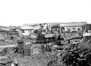 Erster Weltkrieg : Deutsche Soldaten und Arbeiter auf einer Lokomotive mit Güterwagen vor Gebäude mit zerstörtem Dachtuhl