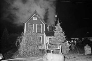 Brand: Zweifamilienhaus: hinten rechts Feuerwehrmänner beim Löschen: hinten Mitte Brandruine: vorn Schlauchrolle: Nacht