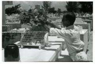 Ein Besucher arrangiert Blumen auf einem Friedhof in Havanna