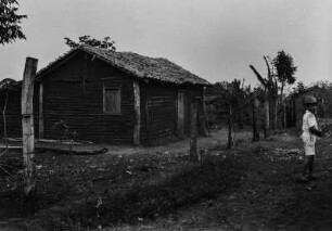Junge vor einem Haus : Ein Junge auf einer Straße vor einem Holzhaus.