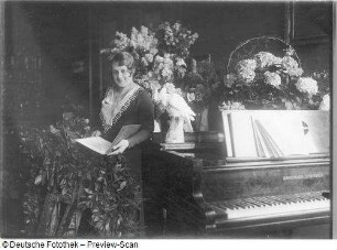 Elisabeth Rethberg mit Blumenarrangement und Geschenken : Porträt Elisabeth Rethberg aus feierlichem Anlaß mit Blumenarrangement und Geschenken in ihrer Wohnung. Fotografie von Ursula Richter, um 1928