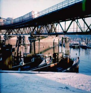 Hamburg. Barkassen im winterlichen Hafen. U-Bahn überquert den Hafen