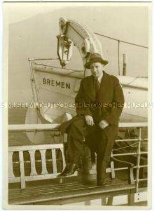 Herr im Mantel an Deck des Hochseepassagierdampfers "Bremen", auf der Reling sitzend