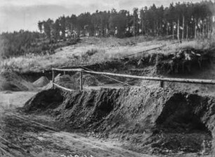 Abgetragener Berghang : Mehrere Haufen liegen am Fuße eines Hanges, von dem Material abgetragen wurde. Oberhalb Waldbestand