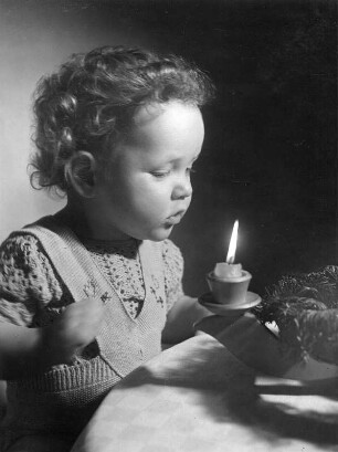 Kinderbilder. Kleinkind vor einer brennenden Kerze