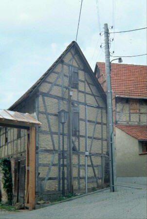 schmale Giebelwand einer Fachwerkscheune, daran neu gebautes Hoftor