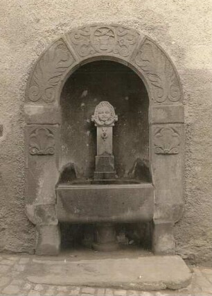Brunnen mit Portalabschluss und drei Steinköpfen