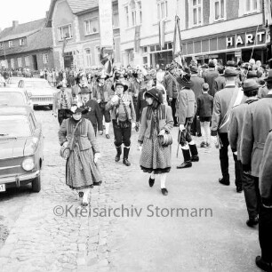 Schützenfest: Veranstalter Schützenverein Reinfeld und Umgebung von 1954 e.V.: Umzug: Paul-von-Schoenaich-Straße: Tiroler Schützen der Schützenkompanie Wilten (bei Innsbruck) mit Standarte, vorne zwei "Marketenderinnen" mit Schnapsfässchen: rechts Schützen [Rückenansicht] mit Fahnen: links Autos, hinten Zuschauer, rechts Geschäft "Harten", 8. September 1968