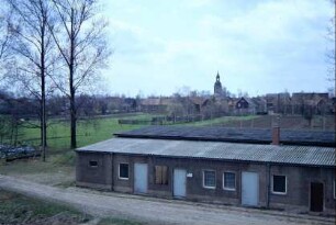 Ortsansicht vom Stausee; vorn Flachbau der Wasserwirtschaft, hinten Dorf