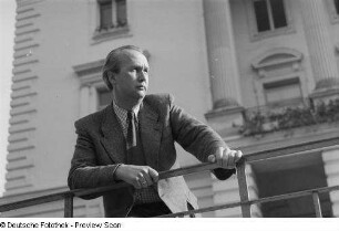 Portrait eines Mannes an einem Geländer, im Hintergrund das Weiße Haus